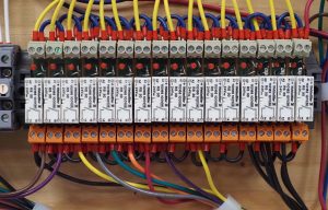 Relay panel — yellow PLC output wires at top, AC device wires at bottom